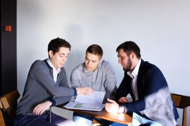 Üç genç erkek programcılar dikkat ederken tablet kullanarak iletişim