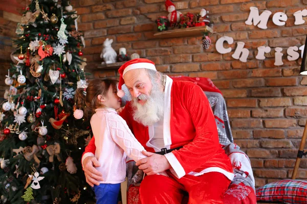 Kleines mädchen umarmt weihnachtsmann und macht weihnachtswunsch in coz — Stockfoto