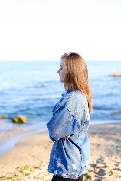 Pretty woman smiles easily and looks at horizon, standing on sho — Stock Photo, Image