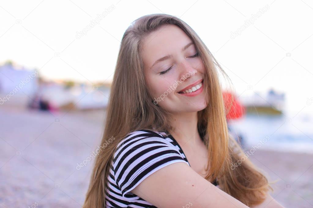 Portrait of beautiful girl who breathes salty sea air, sitting o