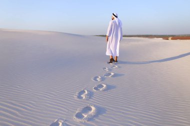 Neşeli erkek Müslüman beyaz kum Çölü yürür ve li sahiptir