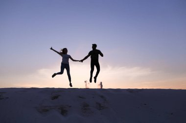 Neşeli adam ve kız eğleniyor ve kumul üstünde dans