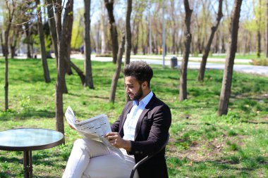 Melez adam caf ve gülümsüyor gazete okuma.