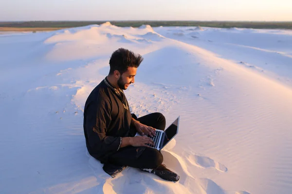 Гарний хлопець з арабських пише на Інтернет, використовуючи ноутбук і сидить — стокове фото