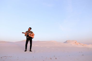 Arap adam çöl güzelliği ile ilham gider ve gitar çi çalış