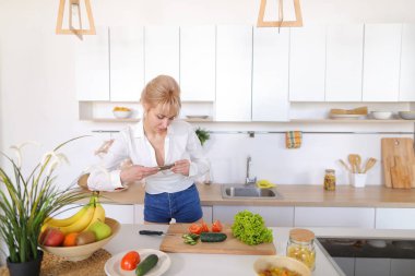 Mutfak kız smartphone elinde tutan ve sebze fotoğrafı çeker