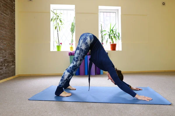 Chica europea de pelo oscuro haciendo calentamiento en la sala de fitness espaciosa — Foto de Stock