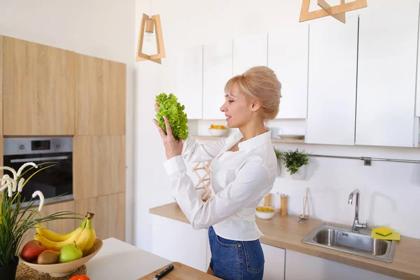 Beautiful housewife woman holding green lettuce leaf and smiling