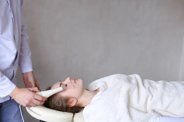 Парень-косметолог делает специальный массаж лица девушке с косметом — стоковое фото