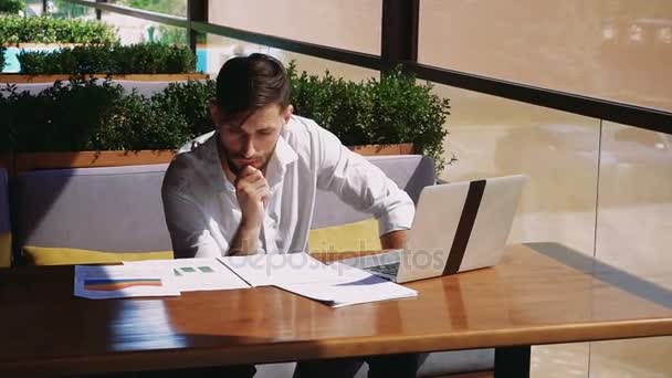 Financier américain travaillant avec un ordinateur portable et des documents de diagramme à la table . — Video