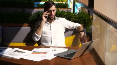 Smartphone ile konuşmak ve laptop ile masada çalışma emlakçı.