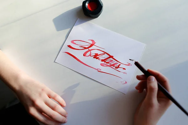 Artista femenina pinta brillante inscripción en hoja de papel con tinta —  Fotos de Stock