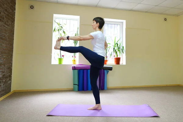 Mulher bonita com cabelos escuros executa exercícios de ioga . — Fotografia de Stock