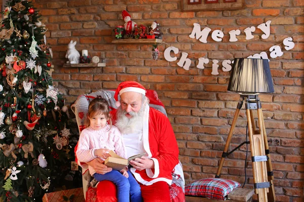 Père Noël est assis sur un fauteuil et lit livre avec des contes de fées fo — Photo