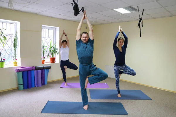 Young woman yoga trainer teaches the boy and girl to do the exer