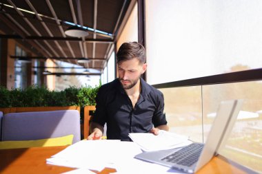 Tablo dizüstü yakınındaki kağıtlara sıralama ofis çalışanı.
