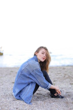 Dinlenme, deniz kenarında oturan ve b kameraya poz güzel kız