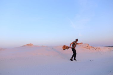 Arap adam çöl güzelliği ile ilham gider ve gitar çi çalış