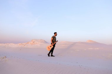 Dese aracılığıyla elinde gitar ile görkemli Müslüman genç adam yürüyor