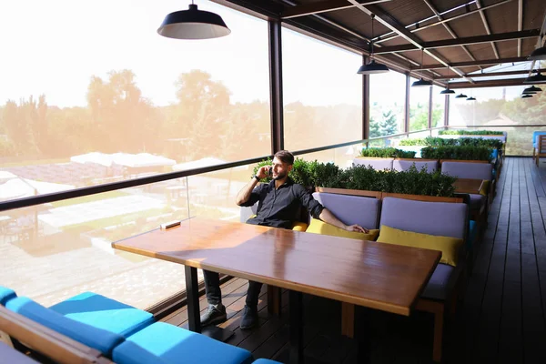 Hombre próspero utilizando el teléfono inteligente para la conversación un banco de energía un — Foto de Stock