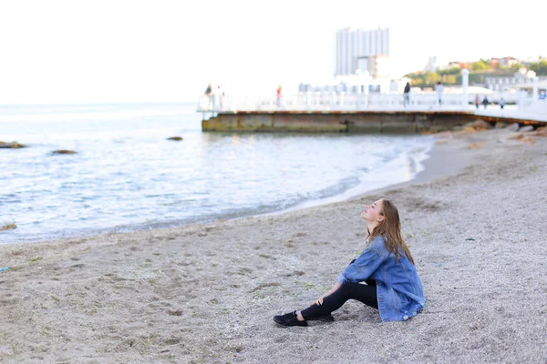 Молодая женщина расслабляется сидя на пляже и наслаждается видом. — стоковое фото