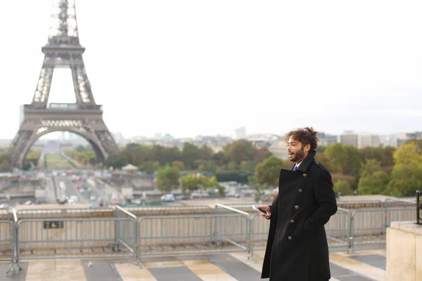Mulatto nevető srác ezen a környéken: Eiffel-torony, smartphone — Stock Fotó