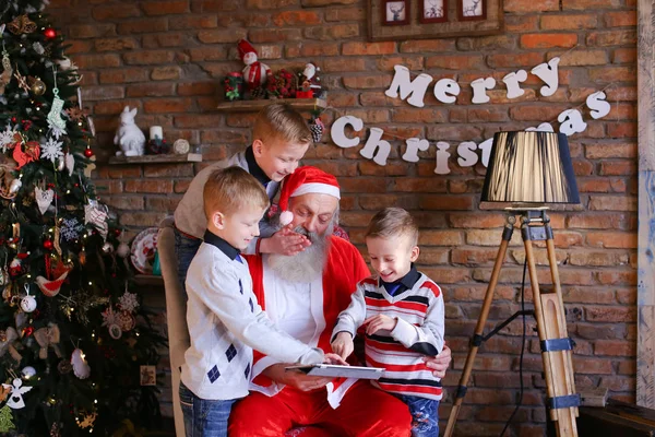 Irmãos amigáveis pedir Papai Noel para incluir desenhos animados em tablet — Fotografia de Stock