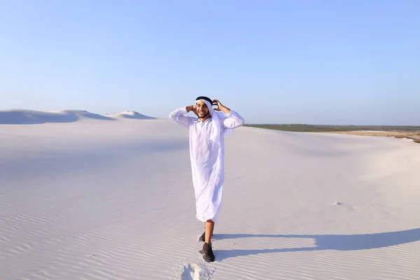 Felice uomo arabo cammina in mezzo al deserto bianco e gode la vita o — Foto Stock