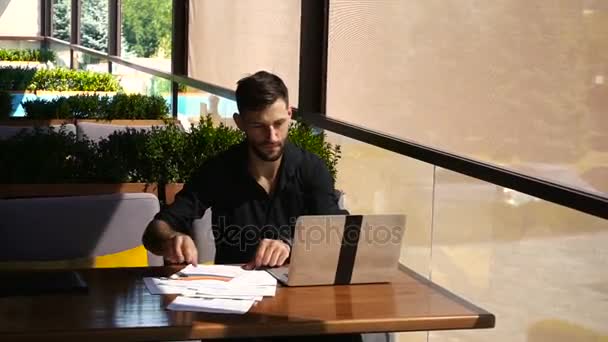 Successful foreman using laptop and documents at cafe. — Stock Video