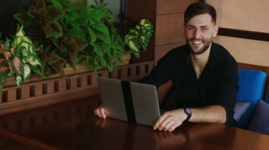 Mutlu işadamı laptop ile çalışma ve ağır çekimde konuşuyor kamera bakıyor.