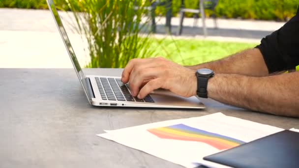 Handen te typen op het toetsenbord van de laptop en documenten op tafel buiten. — Stockvideo