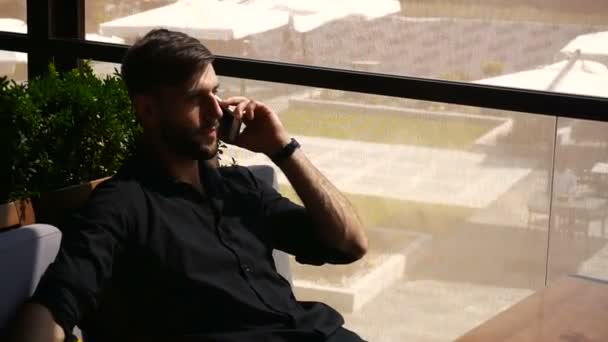 Welvarend man met smartphone voor gesprek een power bank aan tafel. — Stockvideo