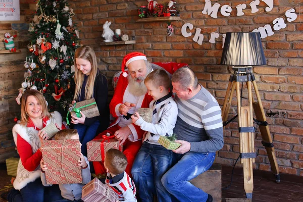 Papá Noel da regalos de Año Nuevo a la gran familia en la habitación decorada — Foto de Stock