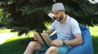 Çanta sandalyede oturan ve dizüstü bilgisayar ile canlı akışı favori spor takımı destekleyen jocund eğlenceli.