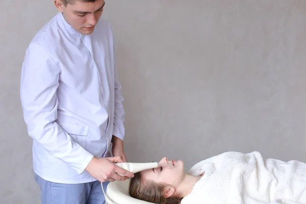 Cosmetologist guy makes special face massage to girl with cosmet — Stock Photo, Image