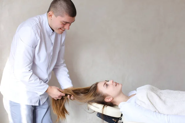 Красивый парень массажист делает массаж головы для девушки. — стоковое фото
