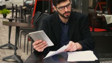 Ağır çekimde kafeterya masada Tablet ve kağıtları ile çalışan grafik tasarımcı.