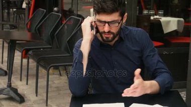 Emlakçı müşteri ile ağır çekimde kafeterya masada telefonla konuşuyor.