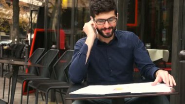Cafe masa raporları ile smartphone tarafından asistanıyla konuşmaya başarılı iş adamı.