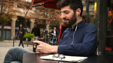 Amerikalı çocuk Café earphones ve ağır çekimde smartphone ile müzik dinlemek.