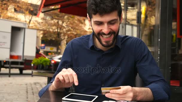Молодой отец покупает онлайн с помощью карты на смартфоне в кафе в замедленной съемке . — стоковое видео