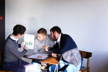 Üç genç erkek programcılar dikkat ederken tablet kullanarak iletişim