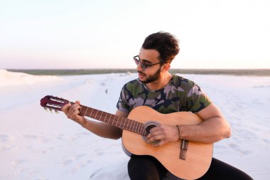 Sevimli genç erkek Arap ses gitar, Hill'de oturan sahiptir
