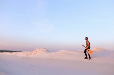 Dese aracılığıyla elinde gitar ile görkemli Müslüman genç adam yürüyor