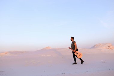 Dese aracılığıyla elinde gitar ile görkemli Müslüman genç adam yürüyor