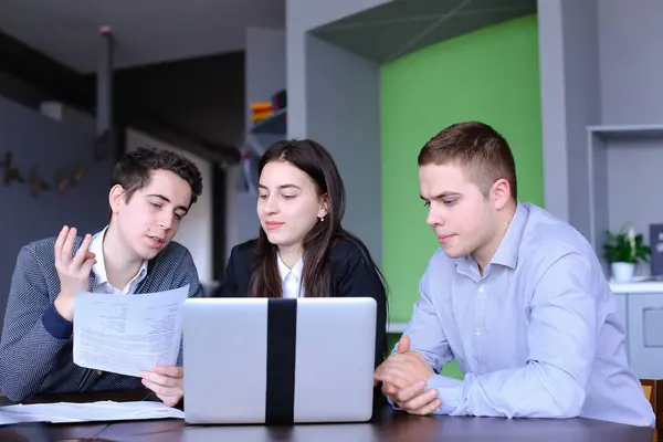 Amistosos amigos de los estudiantes dos chicos y chica están sentados en co — Foto de Stock