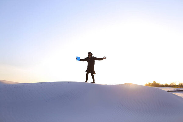 Elevation of male Muslim to top of sand dune over white sand in