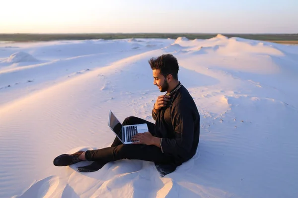 英俊的年轻阿拉伯男子写在互联网使用的便携式计算机上并坐 — 图库照片