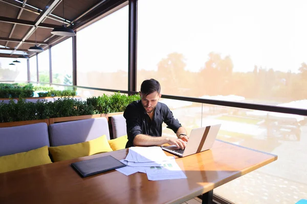 Copywriter typing text on laptop at cafe table.