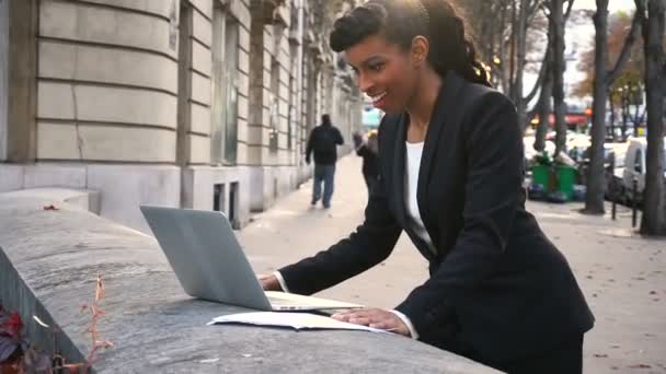 Halb afrikanische Geschäftsfrau telefoniert mit Laptop draußen. — Stockvideo